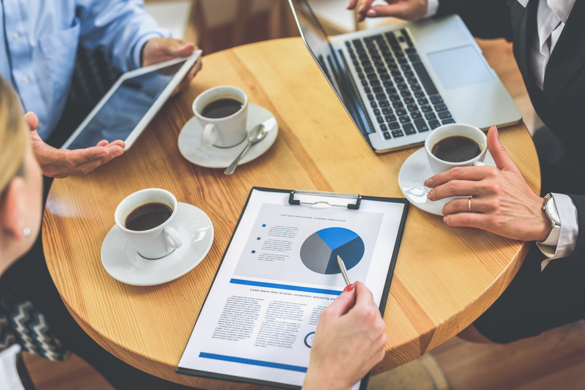 Business team reviewing financial charts and documents during a coffee meeting